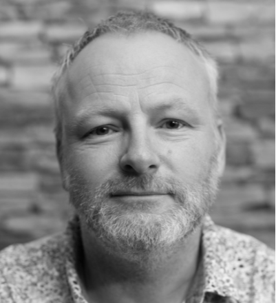 A black and white photo of Craig Hutton with a beard.