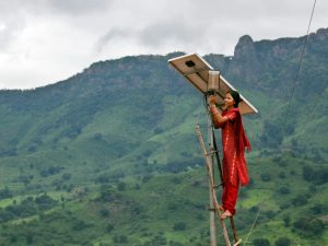 Meenakshi Dewana, a barefoot solar engineer, tends to maintenance work on the solar street lighting in her village of Tinginaput, India: a solar-powered village in the Eastern Ghats of Orissa. She is surrounded by the huge green hills of this rural area.