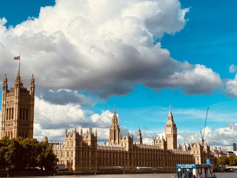 Houses on Parliament against blue sky with huge cloud in background.