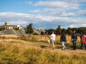 Environmental Sciences students on the UEA campus, walking towards the iconic Ziggurats on a sunny day.