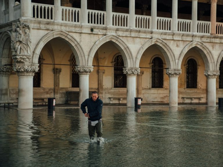 Man walking across a flooded Piazza San Marco in Venice, Italy