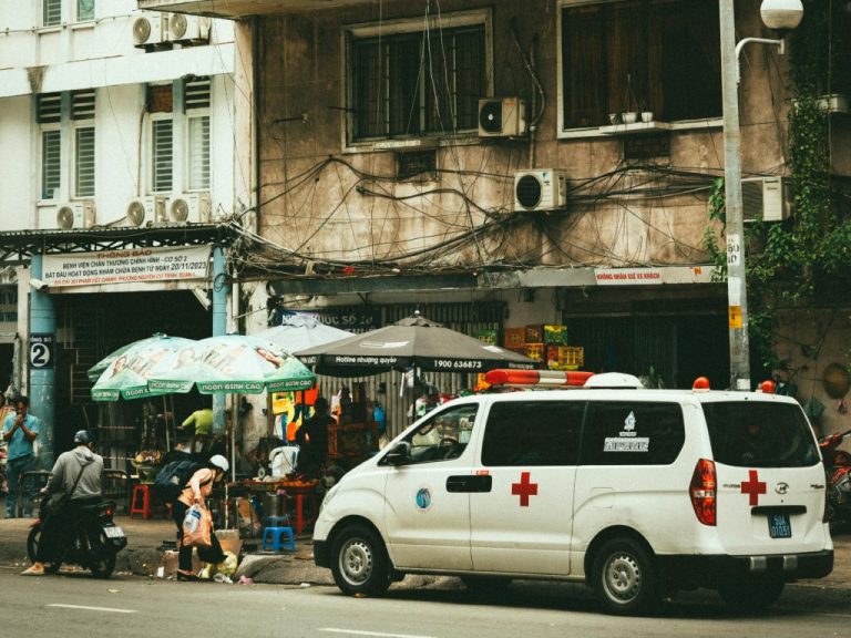 Busy street scene with an ambulance in front of apartment buildings in Ho Chi Minh City, Vietnam.
